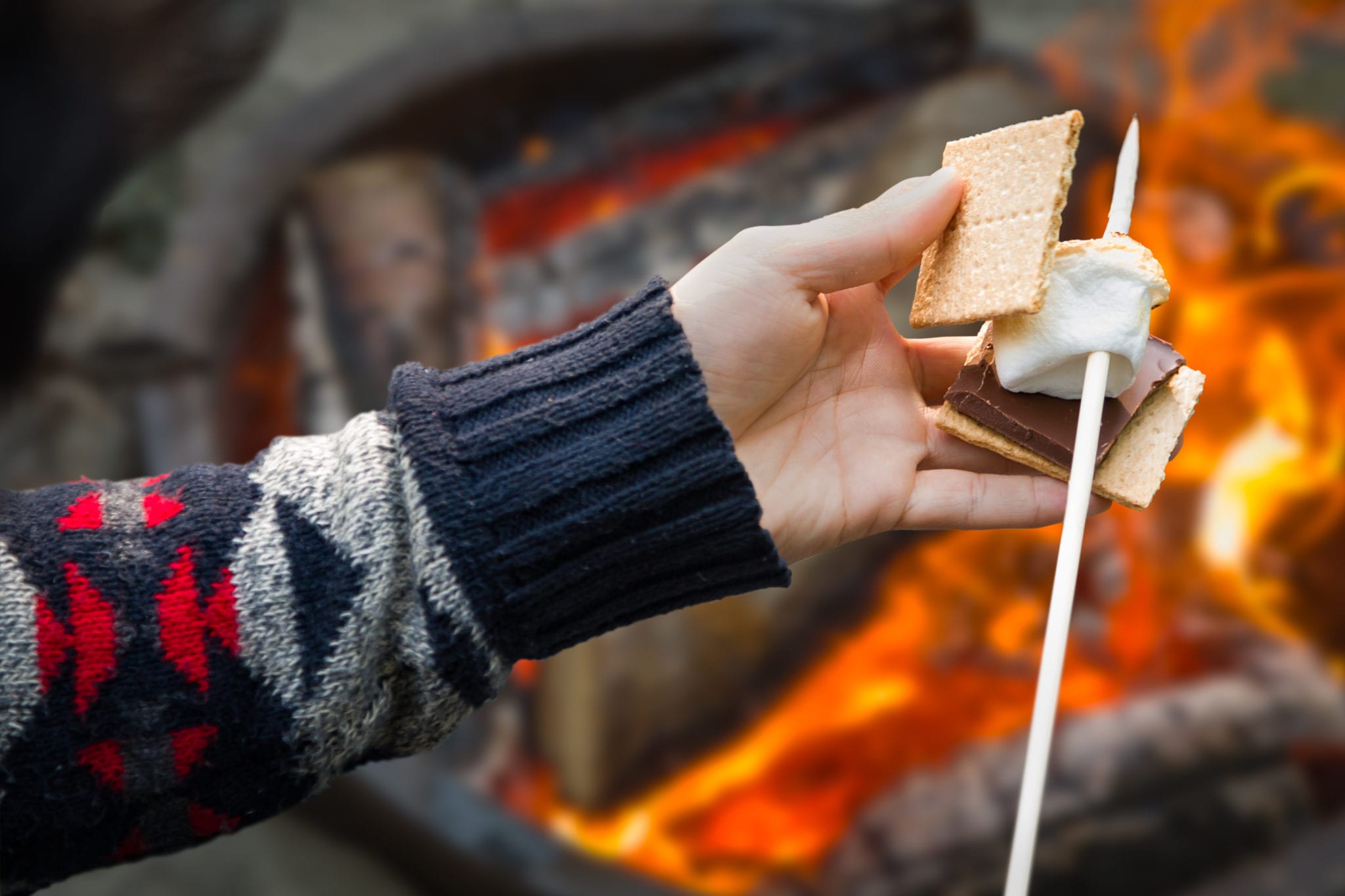 closeup-of-hands-building-smore-with-roasted-marshmallow-and-chocolate